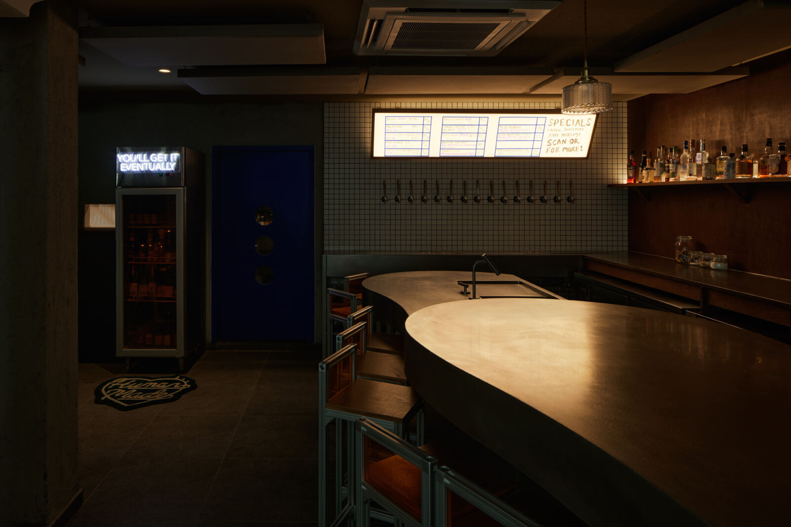 Almost Famous Bar at CHIJMES with dark hospitality counter, tap wall and warm architectural lighting by The Local INN.terior
