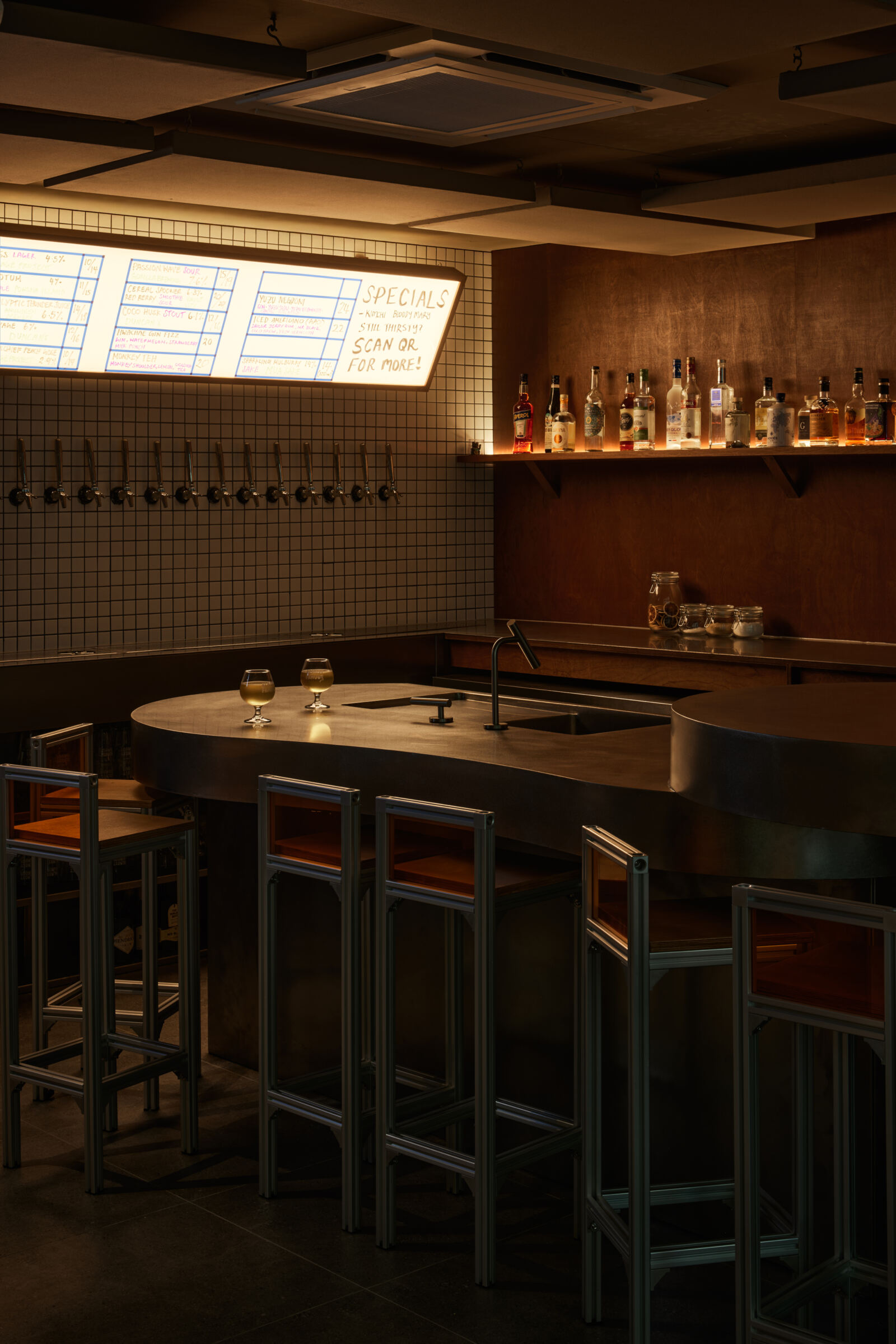 Almost Famous Bar at CHIJMES with curved counter, metal stools and illuminated tap wall by The Local INN.terior